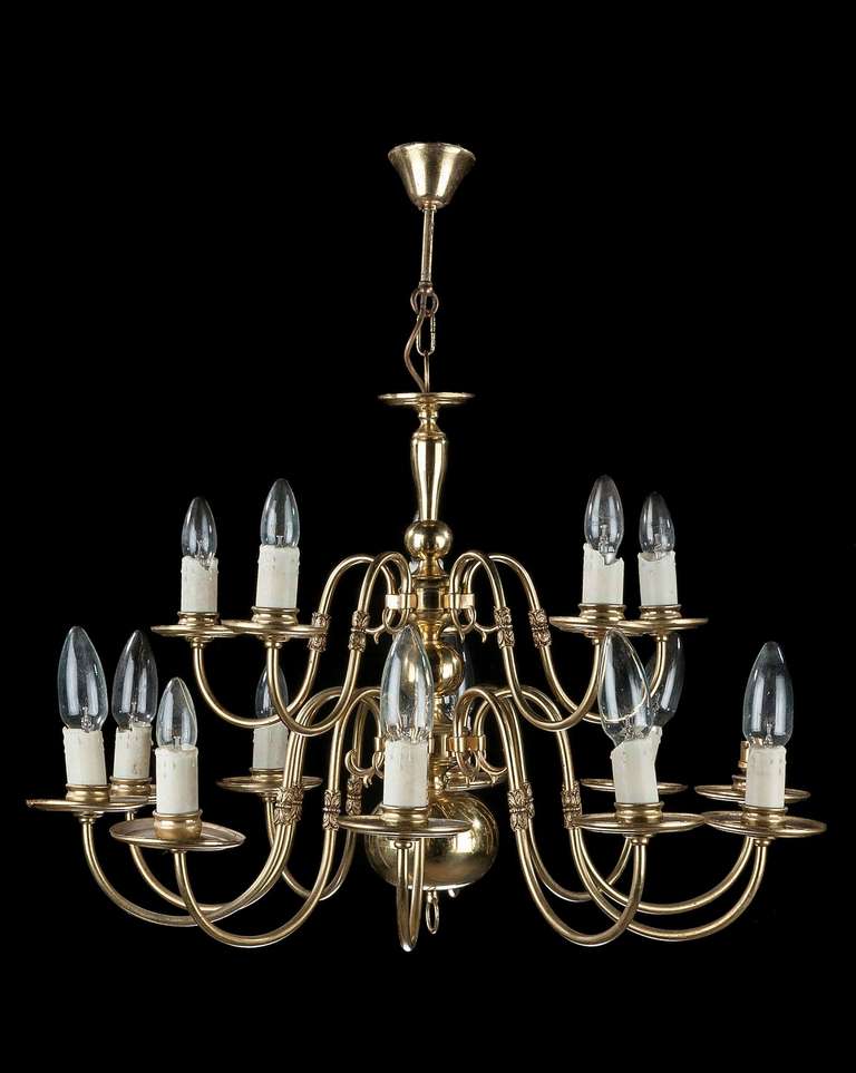 A twelve-arm tiered brass and gilt bronze chandelier, the scroll arms with substantial drip patterns, the center with bulbous and slender turnings.

