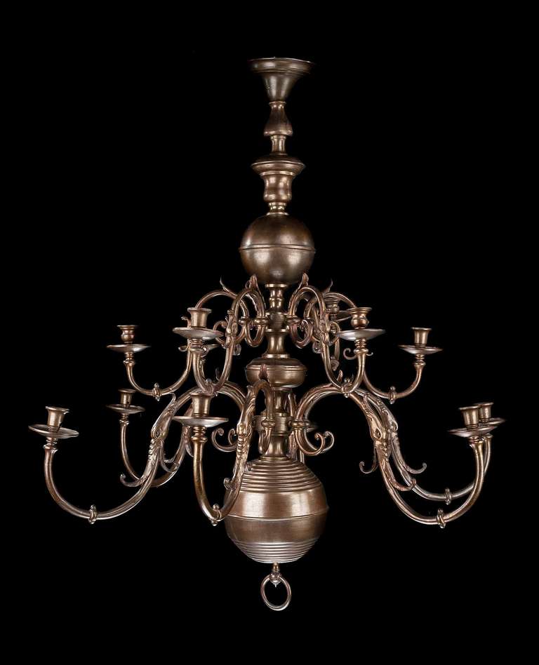 A late 19th century two-tiered bronze twelve-arm chandelier of late 17th century design, scrolling arms with flared leafs, balluster to centre section, antique light bronze color.

