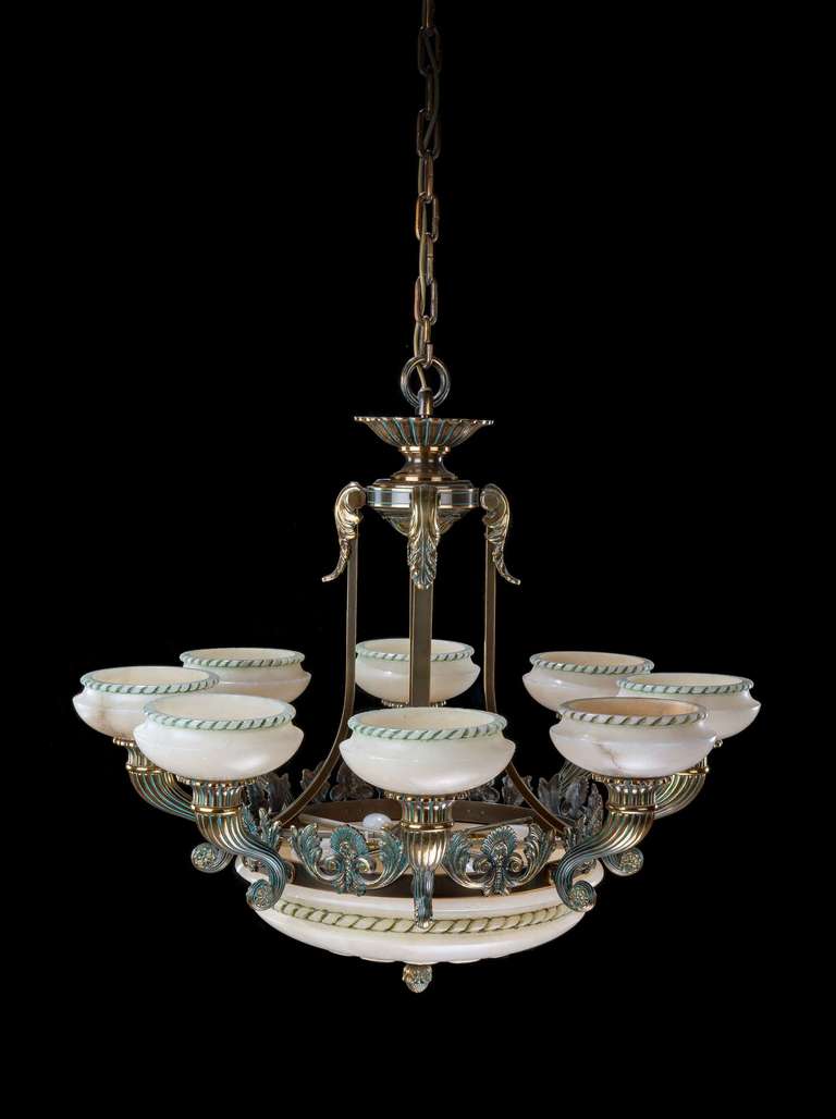 A large alabaster and gilt bronze chandelier with eight scrolling arms joined by masks and foliage in the centre section.
