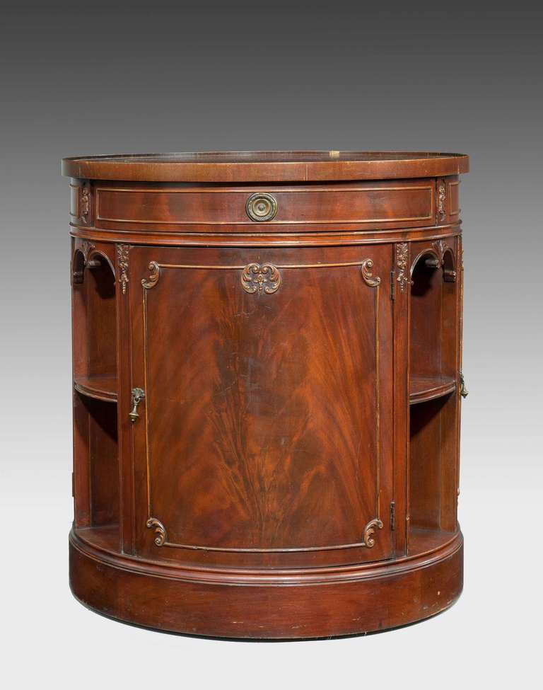 An unusual Revolving mahogany Library Table with cupboard sections divided by book shelves. Inset wine coloured leather top, the upper freeze with suspended drawers with a decorated gilt bronze edging. Late 20th Century.