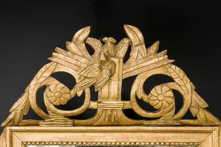 An 18th century period giltwood mirror with swags to the sides and stylized top incorporating a bird.

