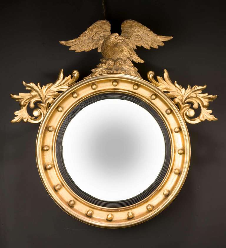 A good Regency period circular convex mirror, the upper section with foliage and a vigorously carved eagle.


