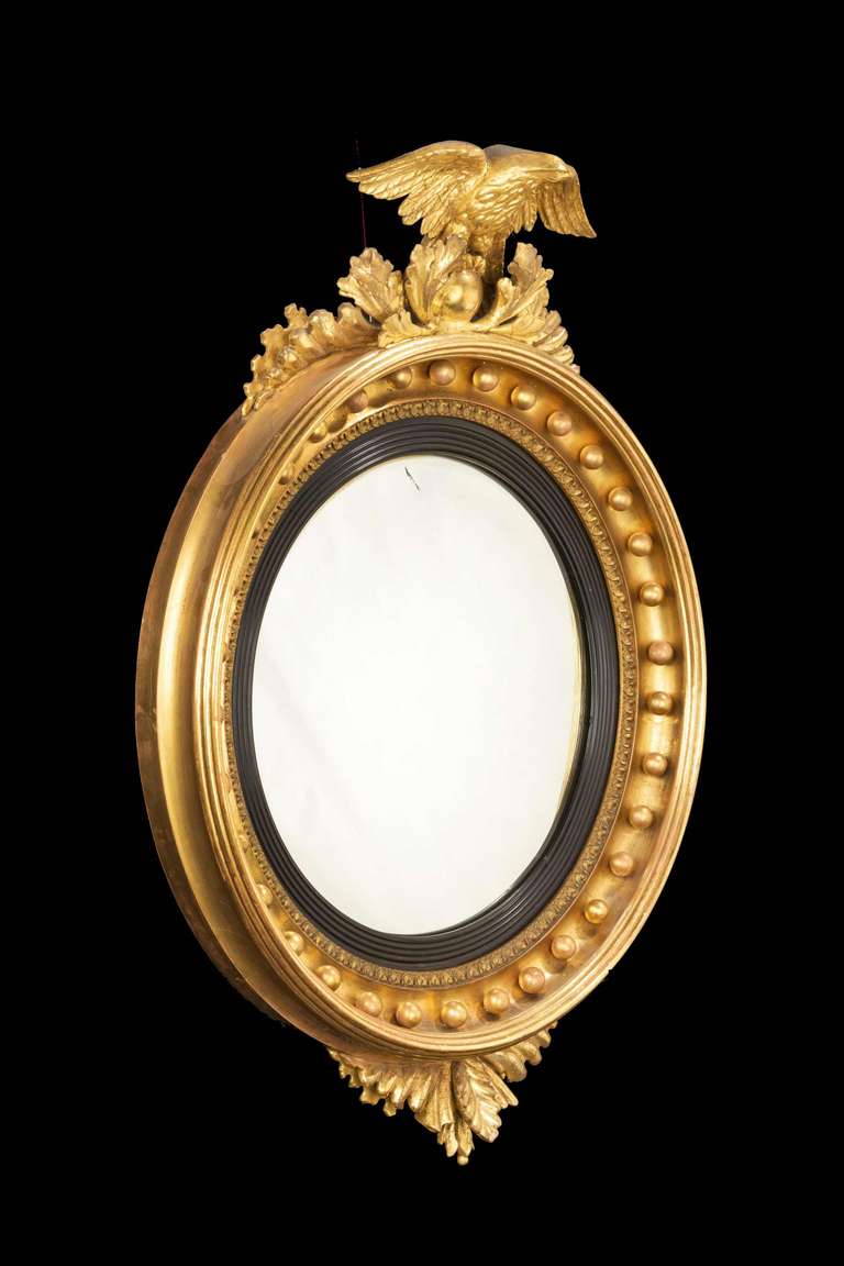 A good Regency period circular convex mirror, the upper section with foliage and a small carved eagle.


                  