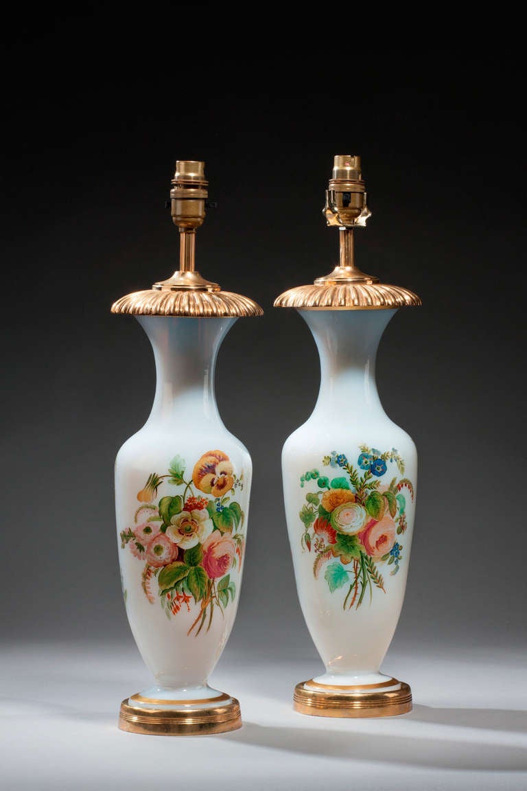 Pair of white ground French opaline vases, early 20th century, now converted with custom-made tops and bases into lamps. Enameled with peonies, roses and convolvulus.

Shades are not included in the price of our lamps. 

RR.