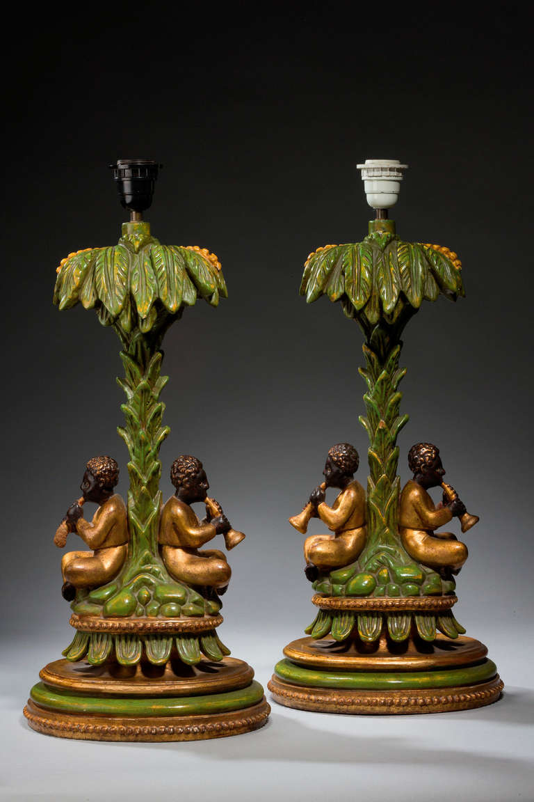 Pair of unusual polychrome and gilded lamps, with children playing horns under the stems of palm trees, mid-20th century.

Shades are not included in the price of our lamps. We do have a competitively priced range of shades for all of our
