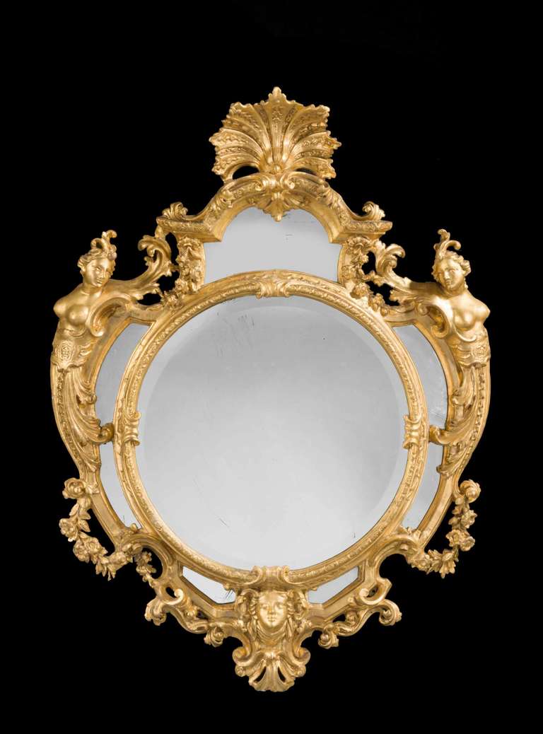 A very fine mid-18th century Italian giltwood mirror, the centre circular section with simple elaborate scrolling to the outer sections, the top with an elaborate finely carved cartouche, the whole vigorously carved, the extreme outer left and