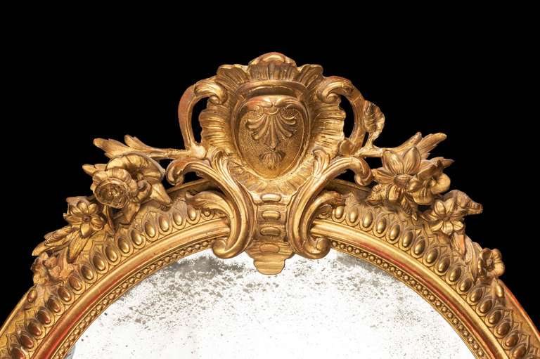 A fine Chippendale period oval mirror with inner bead carved border surrounded by an egg and dart section all within a concave outer edge. The top with a fine and elaborate cartouche framed within an elaborate surround.

