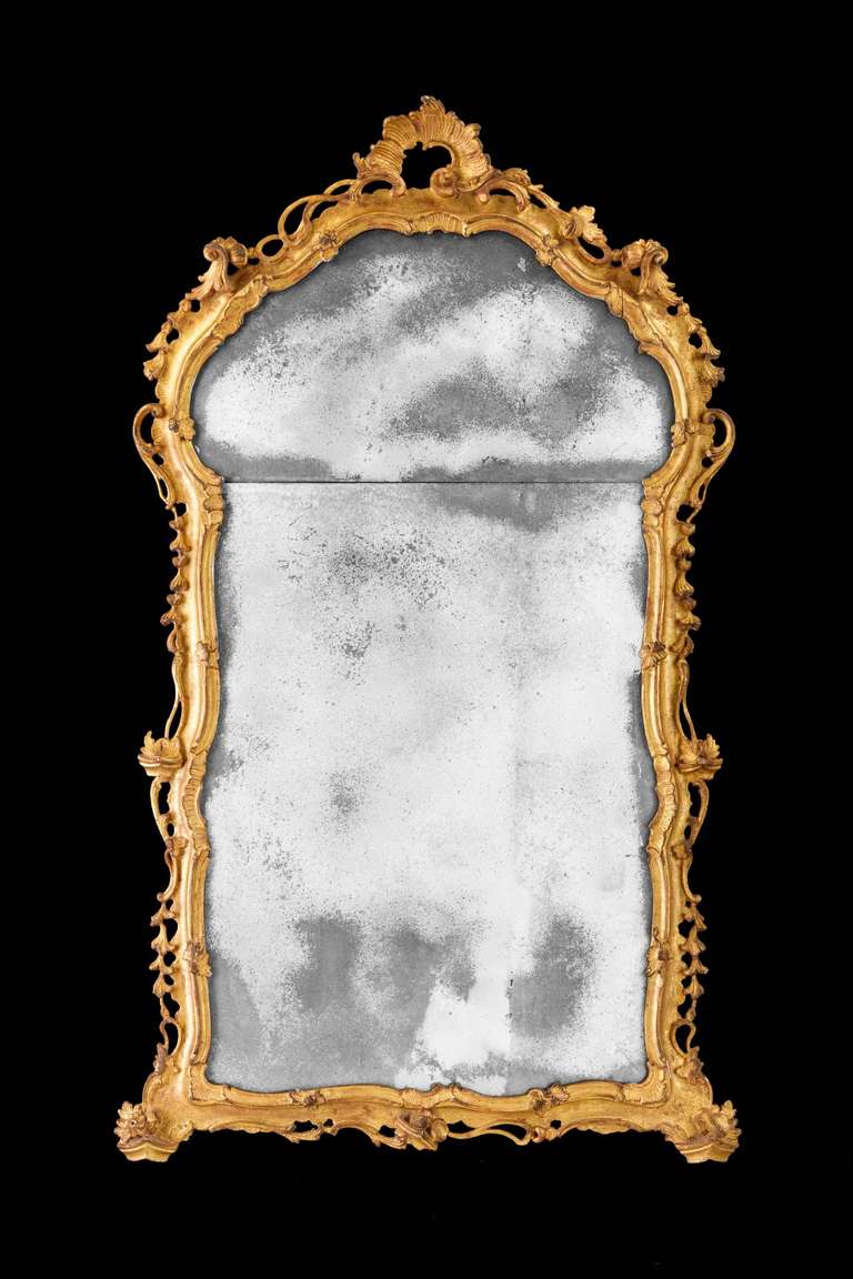 A fine 18th century carved giltwood mirror, the continuously carved arch with folios and shaped borders, the top with a pierced stylised shell in very good overall condition, period plates.


 