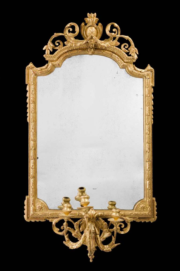 A mid-19th century very elaborate gesso and giltwood pier mirror, the top of continuous scroll work surmounted with a cartouche, the bottom section incorporating a candelabra.

