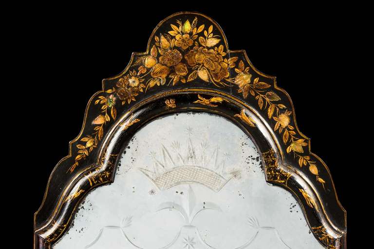 An early 18th-century lacquered mirror in the oriental style, the fine cushion frame with foliage and birds and minor landscapes, the top very well gilded with flowers and well-shaped, the mirror finely engraved with a coronet.
