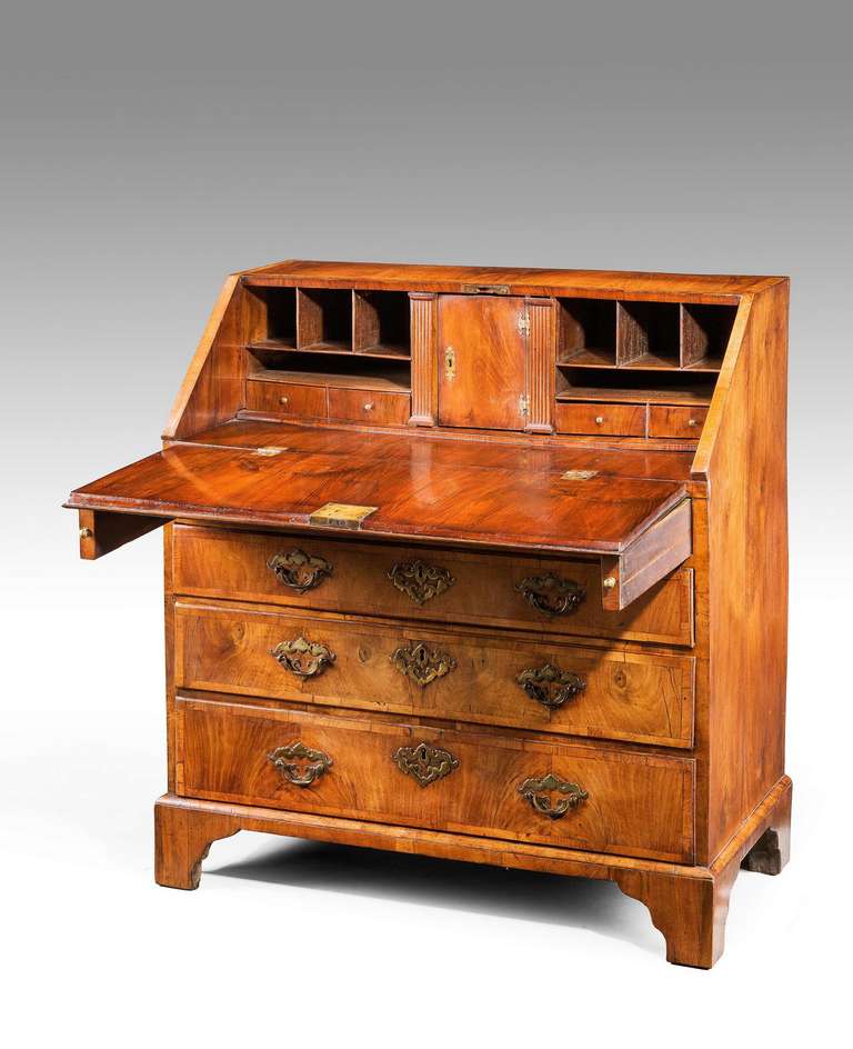 A mid-18th century George II period walnut bureau, the fall front crossbanded with broad crossbanding, the drawer fronts matching but on a smaller scale, standing on period bracket feet, the interior with a central door with secret compartments,
