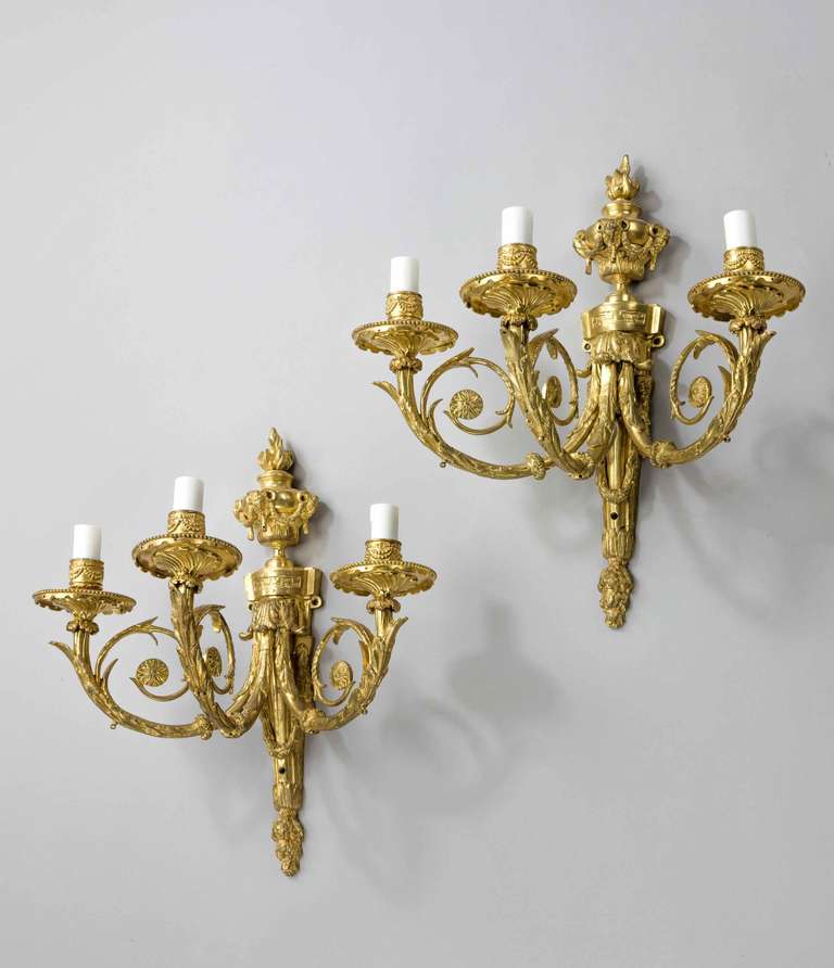 A fine quality pair of late 19th century three-arm wall lights, gilt bronze, retaining the original surfaces, the top section an urn surmounted with ram's heads and swags, the centre with three scroll arms.
