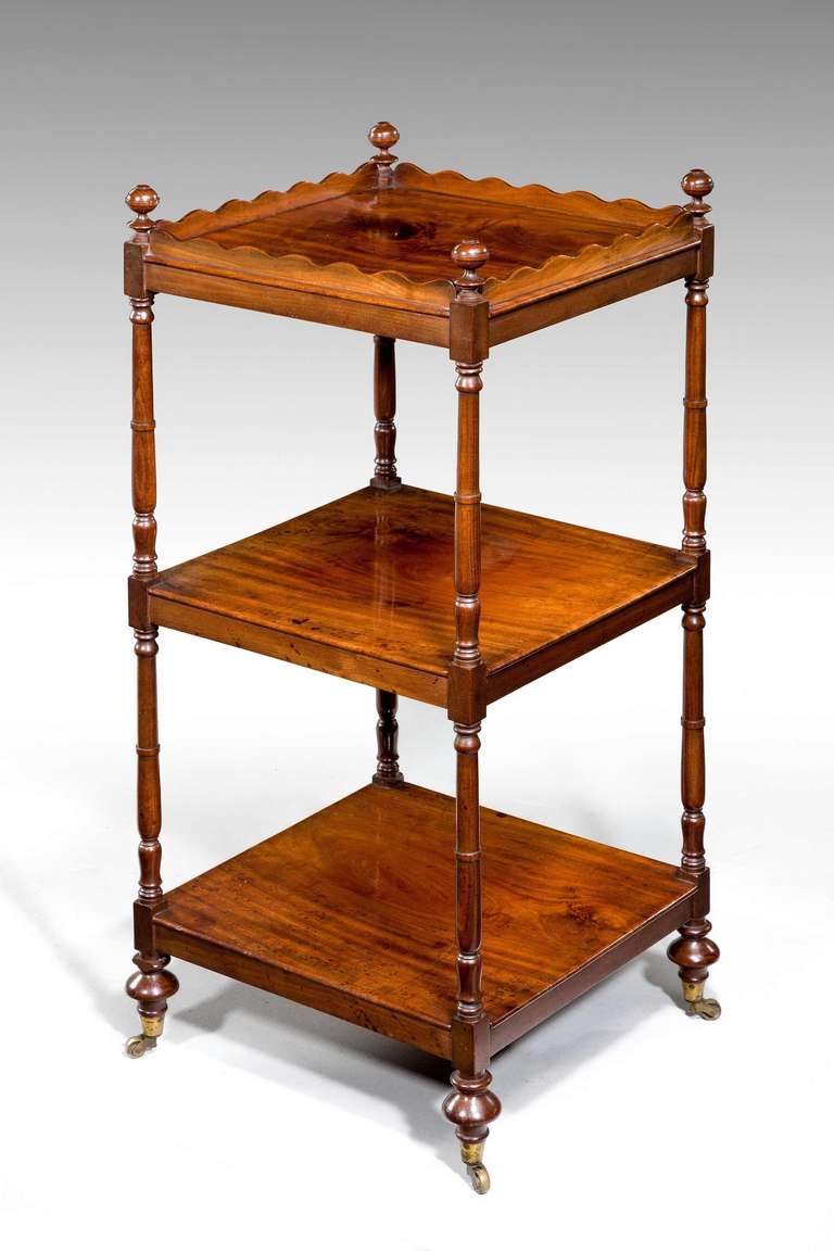 An elegant George III period mahogany étagère of good color and patina and with finely turned corner supports, the top shelf with a wavy gallery, original shoes and castors.

RR.