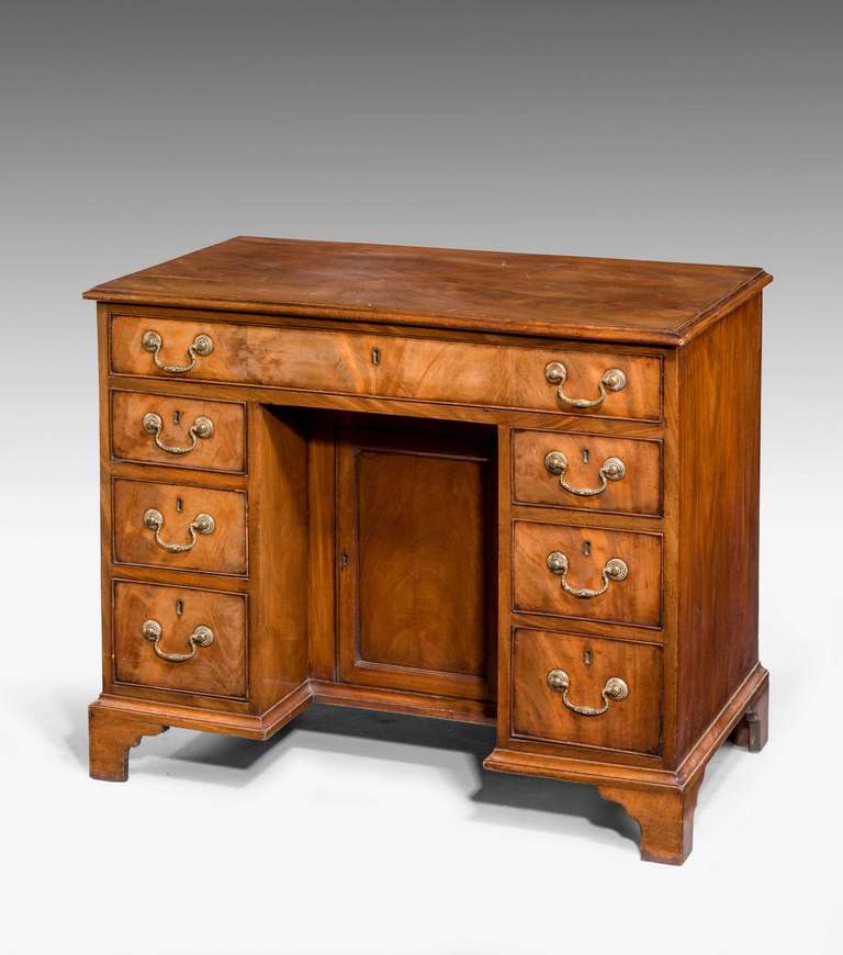 A good George III period mahogany kneehole desk, the timbers particularly good quality and well-chosen, the top highly patinated, original gilt swan neck handles, the recess cabin door with a well carved moulding.