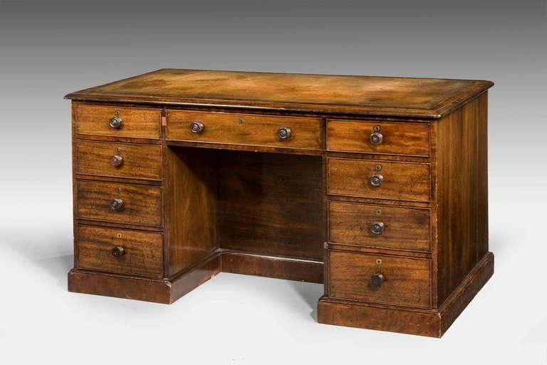 An attractive Regency period mahogany one part (fixed) pedestal desk, the facing side with nine drawers retaining original period knobs, inset leather top, the leather possibly, circa 1900 with refreshed gilded Greek key pattern, the reverse side