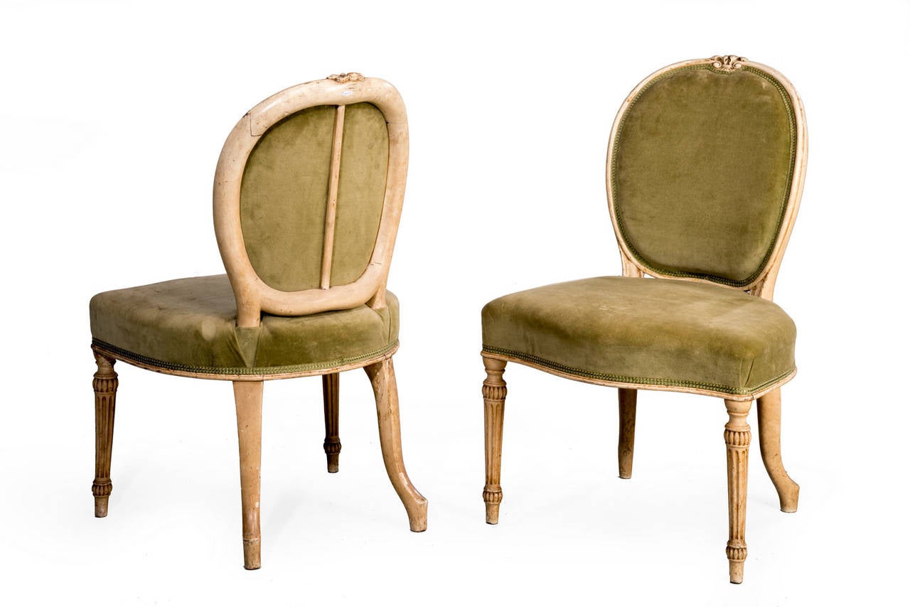 An attractive pair of Adam period painted single chairs. The oval backs mounted with well carved cartouche, the paint work oxidized and somewhat tired.

