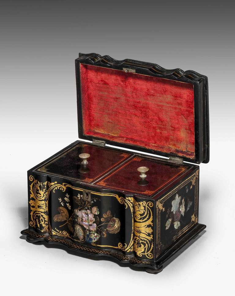 An attractive Regency period papier mâché and mother-of-pearl inlaid tea caddy, multiple serpentine front with Sheffield plated escutcheon. The interior with two compartments retaining silvered paper lining, mother-of-pearl knobs to the lids,
