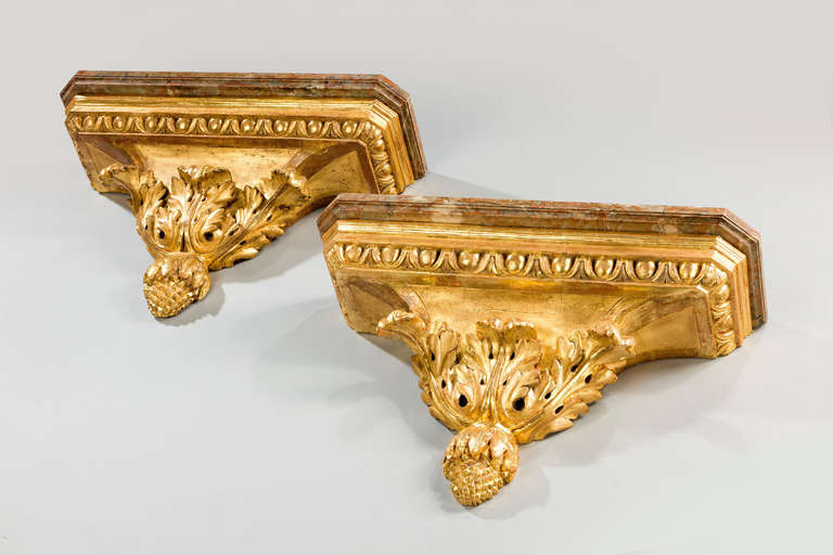 A fine pair of large Italian giltwood brackets and swept base with pineapples and carved leaf decoration, good two-tone gilding retaining original soft greyish and white marble tops.