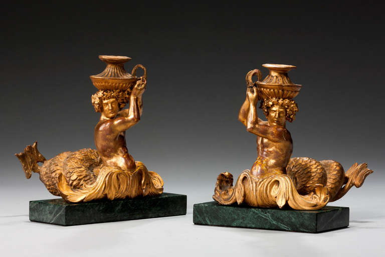 Pair of early 18th century Italian giltwood figures of Mermen on modern marble bases. Mermen are mythical male equivalents and counterparts of mermaids – legendary creatures who have the form of a male human from the waist up and are fish-like from