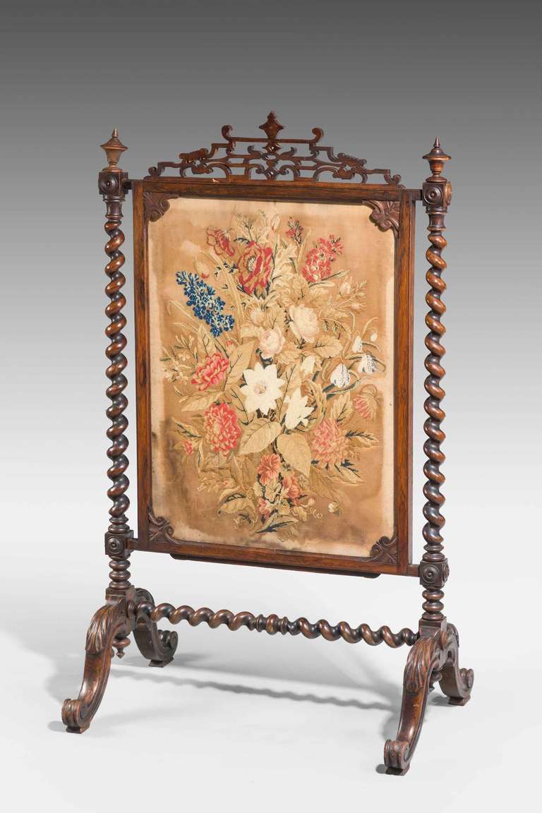 A good 19th century fire screen with well carved writhen supports and stretcher, the top with a pierced pediment, period needlework floral centre panel supported on 'French toes.