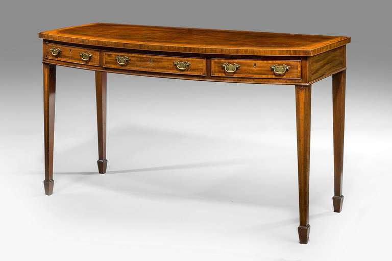 George III period bow front mahogany Serving Table of Sheraton design, broadly cross banded in satinwood the freeze incorporating three drawers on fine tapering supports.

RR