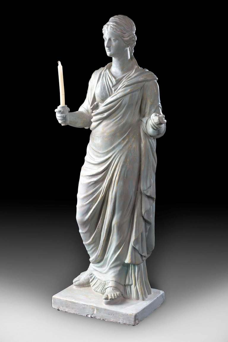 Regency period neoclassical figure of a maiden, her right hand supporting a torchere, the well modelled drapes falling on to a rectangular base.