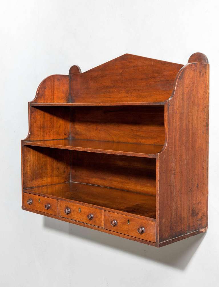 A good George III period mahogany Hanging Shelves, the stepped ends enclosing three drawers