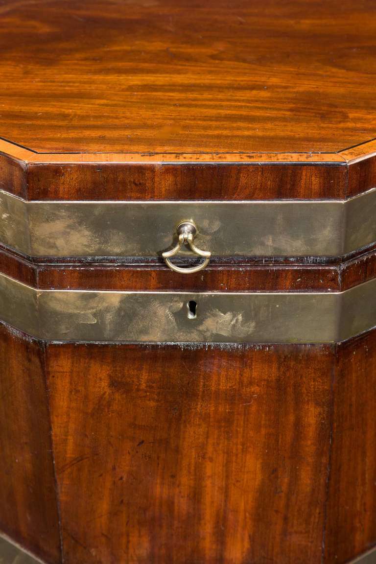 George III period mahogany octagonal wine cooler, the top with original axe handle fittings, the top edge with crossbanding and boxwood inlay, the well carved reeded tapering supports with a band incorporating a circular motif.

