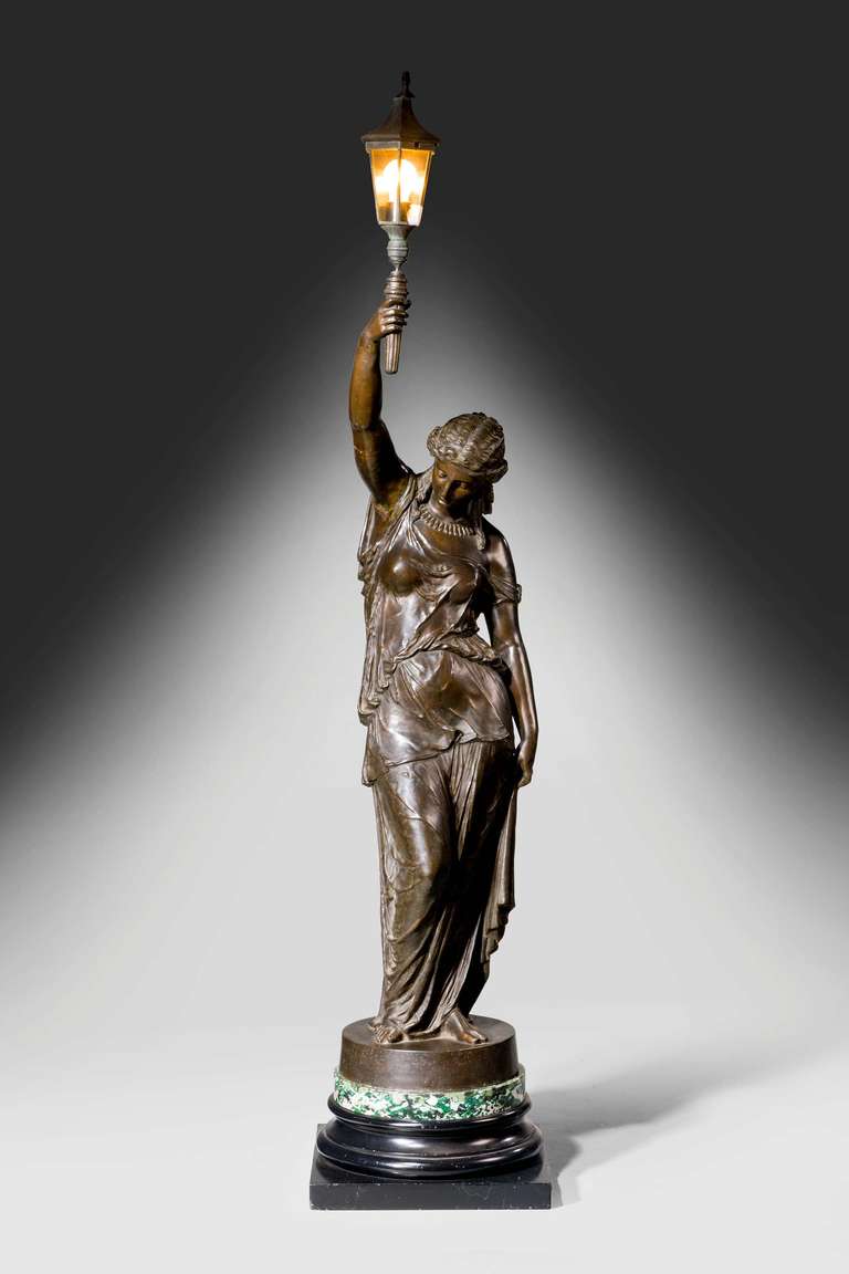 A large bronzed figure of a 19th century neoclassical Maiden, the outstretched arm supporting a lamp. Well cast details, with a rich brown patina.