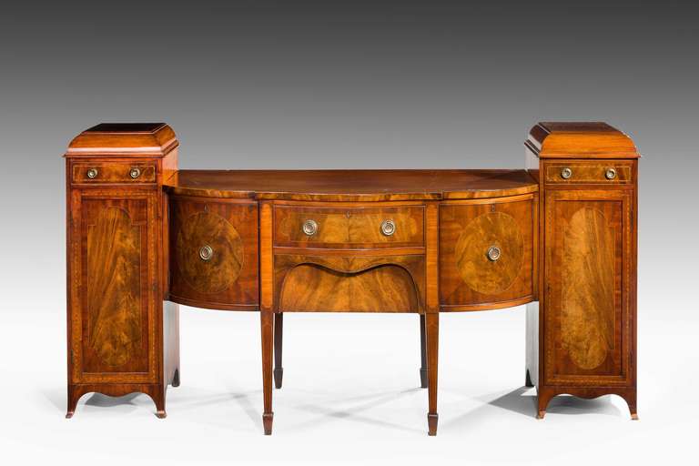 An unusual, late 19th century serpentine and breakfront mahogany sideboard in three sections with fine boxwood and ebony line inlays and highly figured panels in quartered sections, the best construction and brassware.

Provenance:
Sideboards are