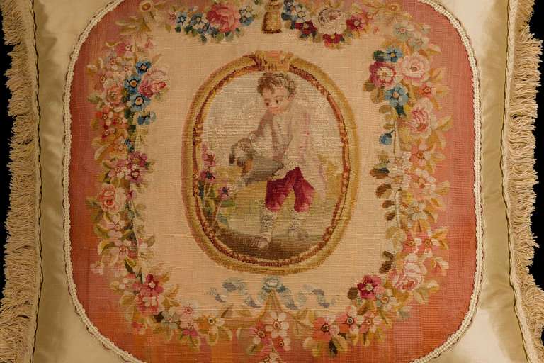 Gobelin, mid-18th century, wool with silk highlights. A child gardening within an oval cartouche, the foliage and old-gold border with soft color edge.

