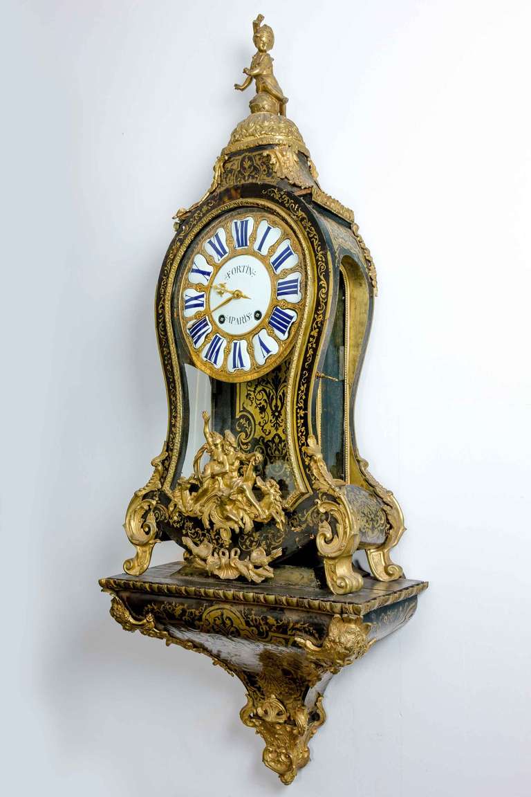 An exceptionally fine and elaborate Louis XV period French Cartel Clock by Nicolas Fortin of Paris. The ebonised base veneers profusely inlaid with cut and gilded brass. The dial with raised enamel numerals. Signed FORTIN PARIS and retaining