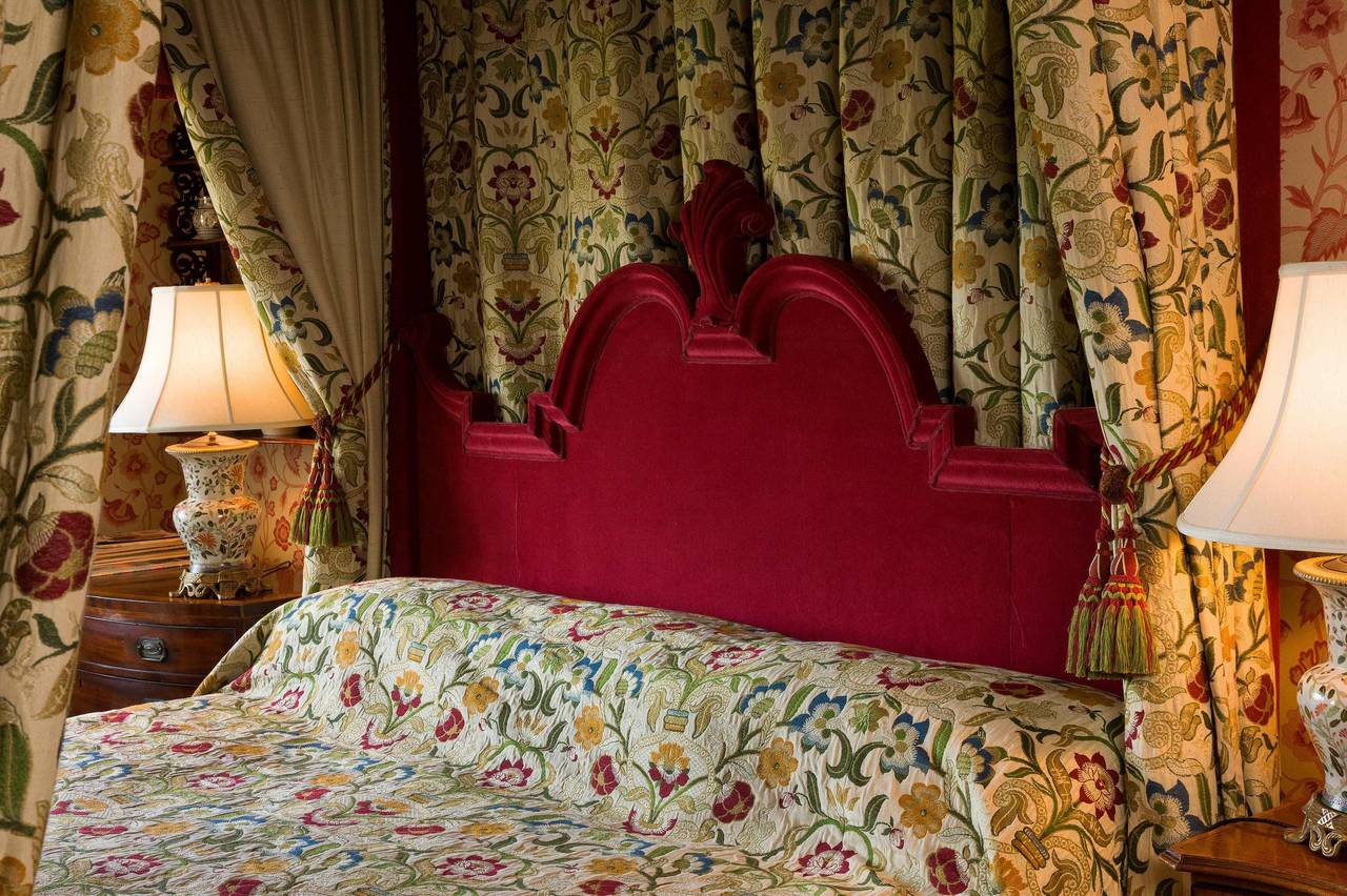 Four-poster bed, large, 17th century style, entirely upholstered in velvet the elaborate cornice with scroll work, a flared upper edge and surmounted with flambe finials, the bed having come from Rathbeale Hall, Swords, Co Dublin the property of