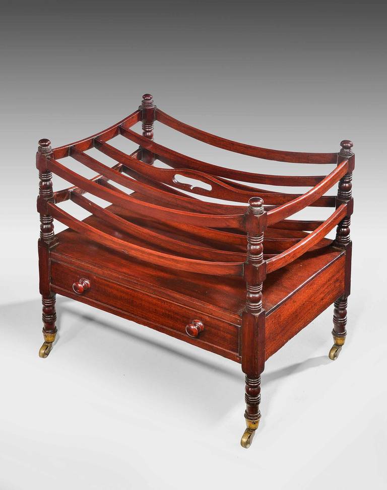 A Regency mahogany canterbury the base incorporating a single draw, retaining original brass shoes and casters. The top with concave separating sections.

RR.