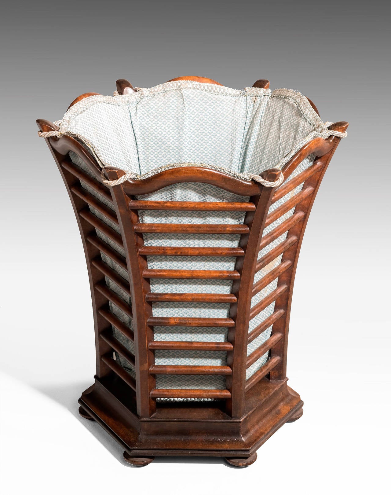 A most unusual flared mahogany waste paper basket with a fabric liner. On original turned feet.

