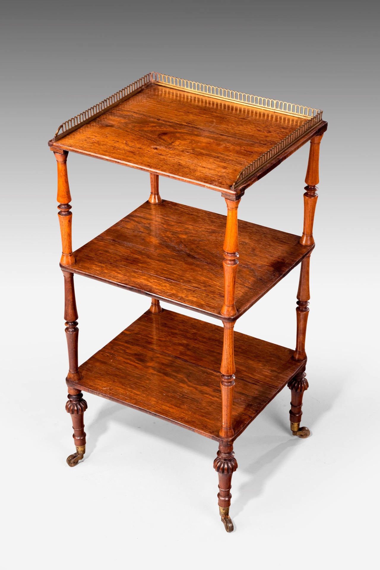 An elegant Regency period etagere. Retaining original border to the top with finely turned supports. Terminating in original shoes and casters.


