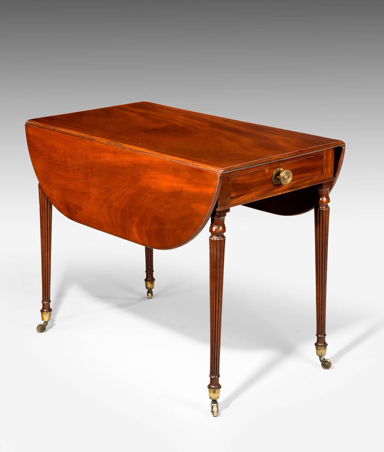 An elegant Regency period mahogany Pembroke table on finely reeded and turned supports, retaining original shoes and casters. Oval shaped with fully open.

Closed dimensions - 19.75 inches.