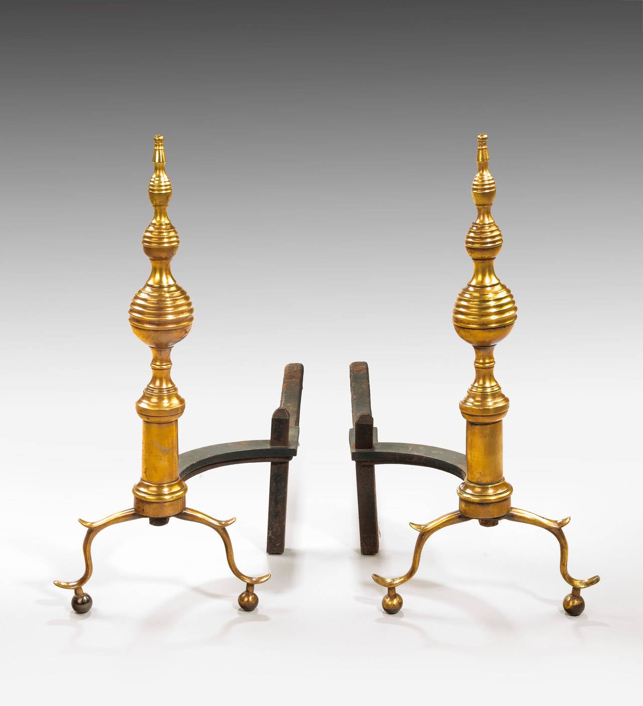 A pair of brass and cast iron andirons, the central sections of bee hive form. On spread terminals.

An andiron is a horizontal iron bar upon which logs are laid for burning in an open fireplace. They are usually used in pairs to build up a