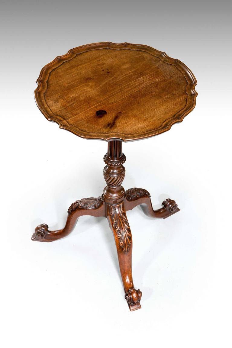 An exceptionally fine Chippendale period mahogany kettle stand with a pie-crust top on a fluted column supported on a finely carved tripod base terminating on a scrolled French foot.

RR.