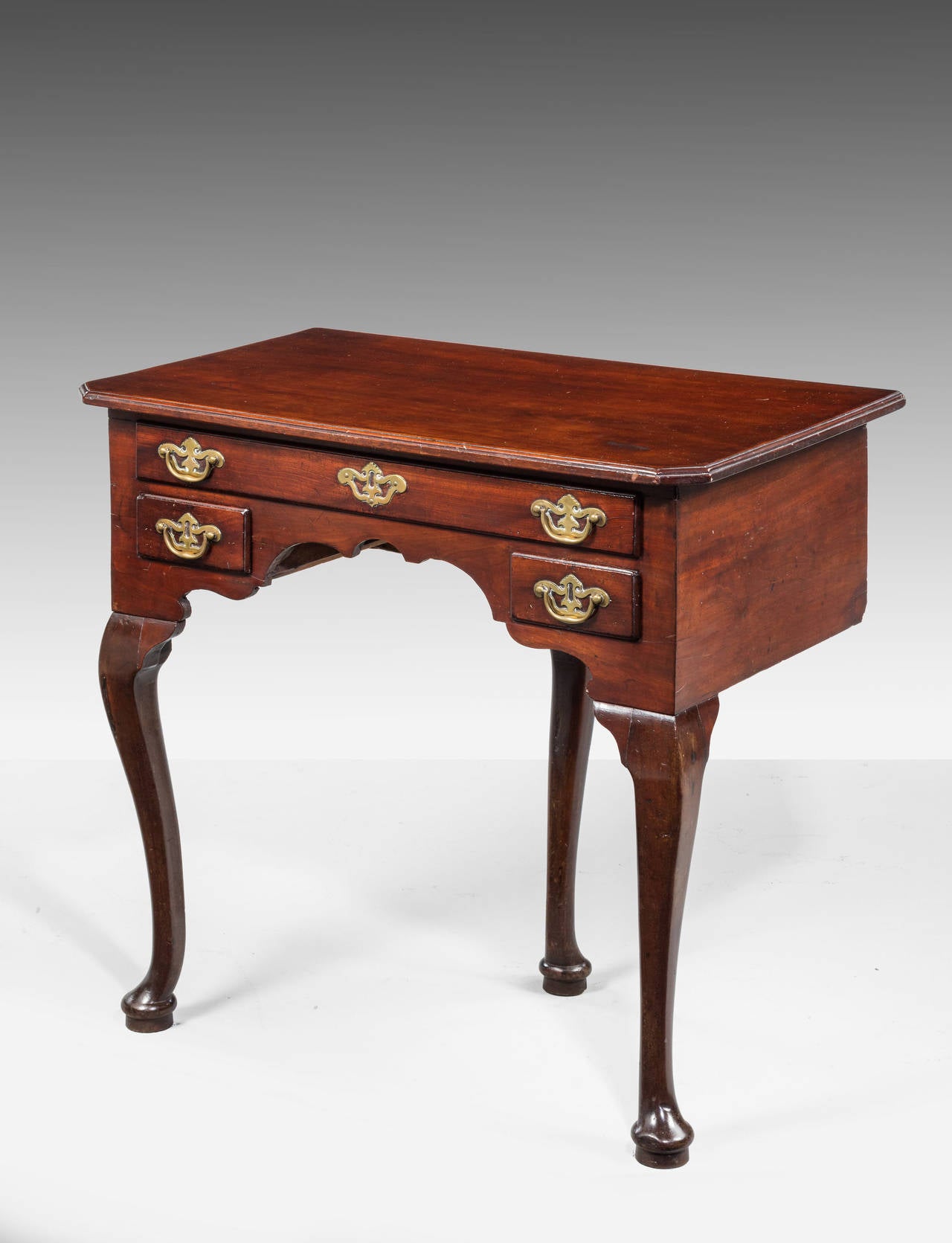 An attractive early George III period mahogany low boy on Cabriole supports. With a single Cabriole leg to the back. Attractive period pieced brass handles chamfered angles to the top.

RR.