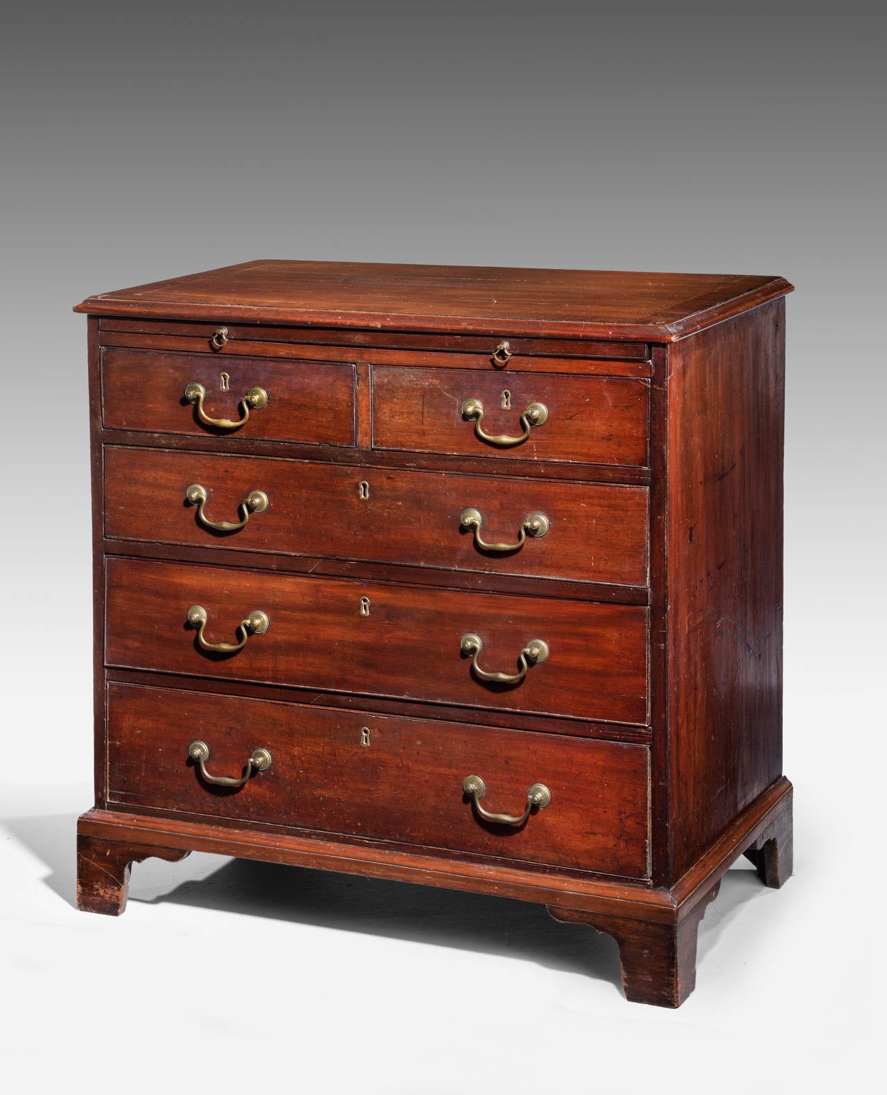An attractive George III period chest of drawers on bracket feet. With substantial and Period swan necked handles. The top incorporating a dressing slide. The top surface cross banded.