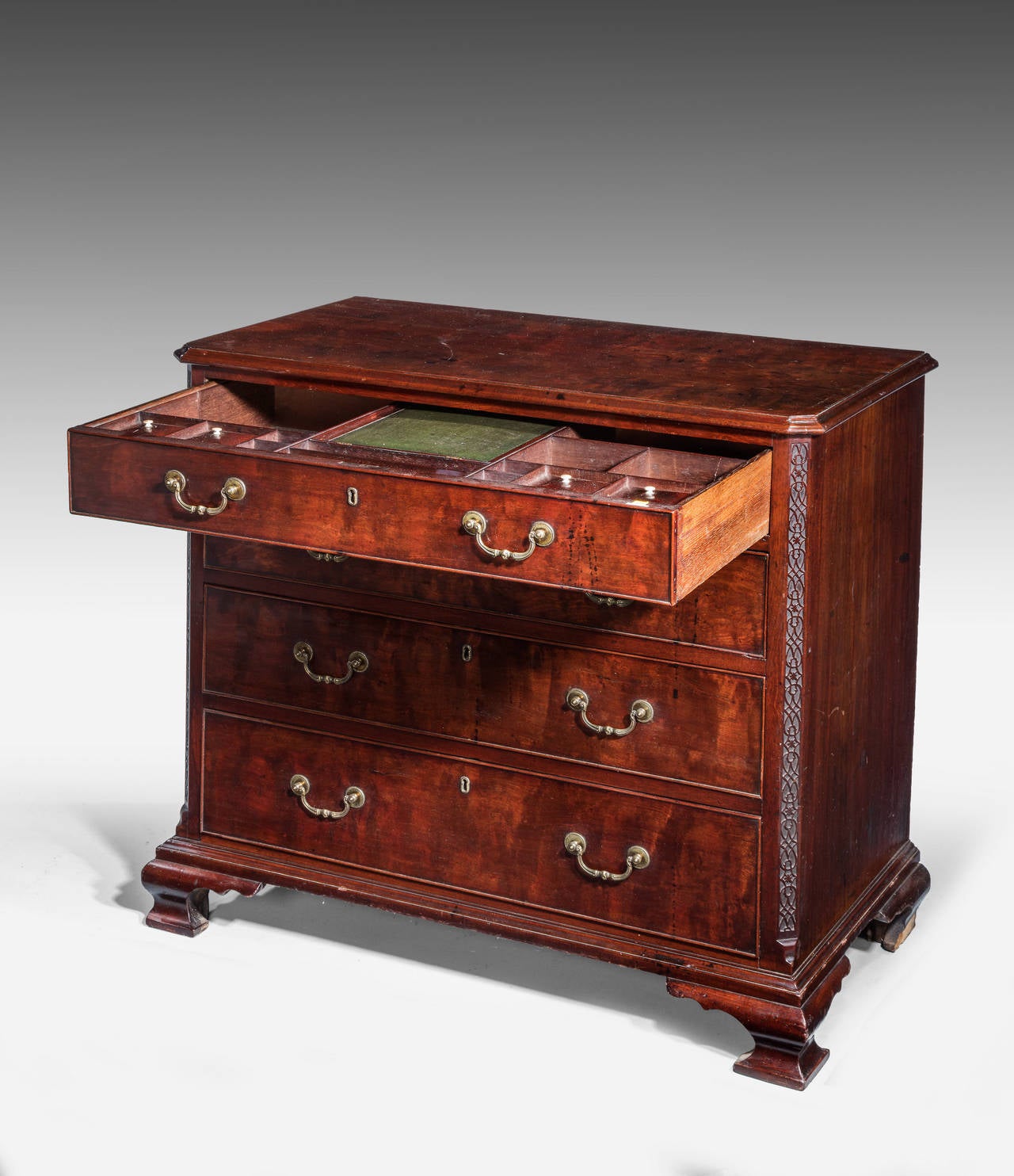 A Chippendale Period Mahogany Chest of Drawers, of very high calibre. The top drawer with fitments with Ivory termini. Cantered corners with very good blind fret carving. Richly figured timbers with good cast swan neck handles. The whole standing on