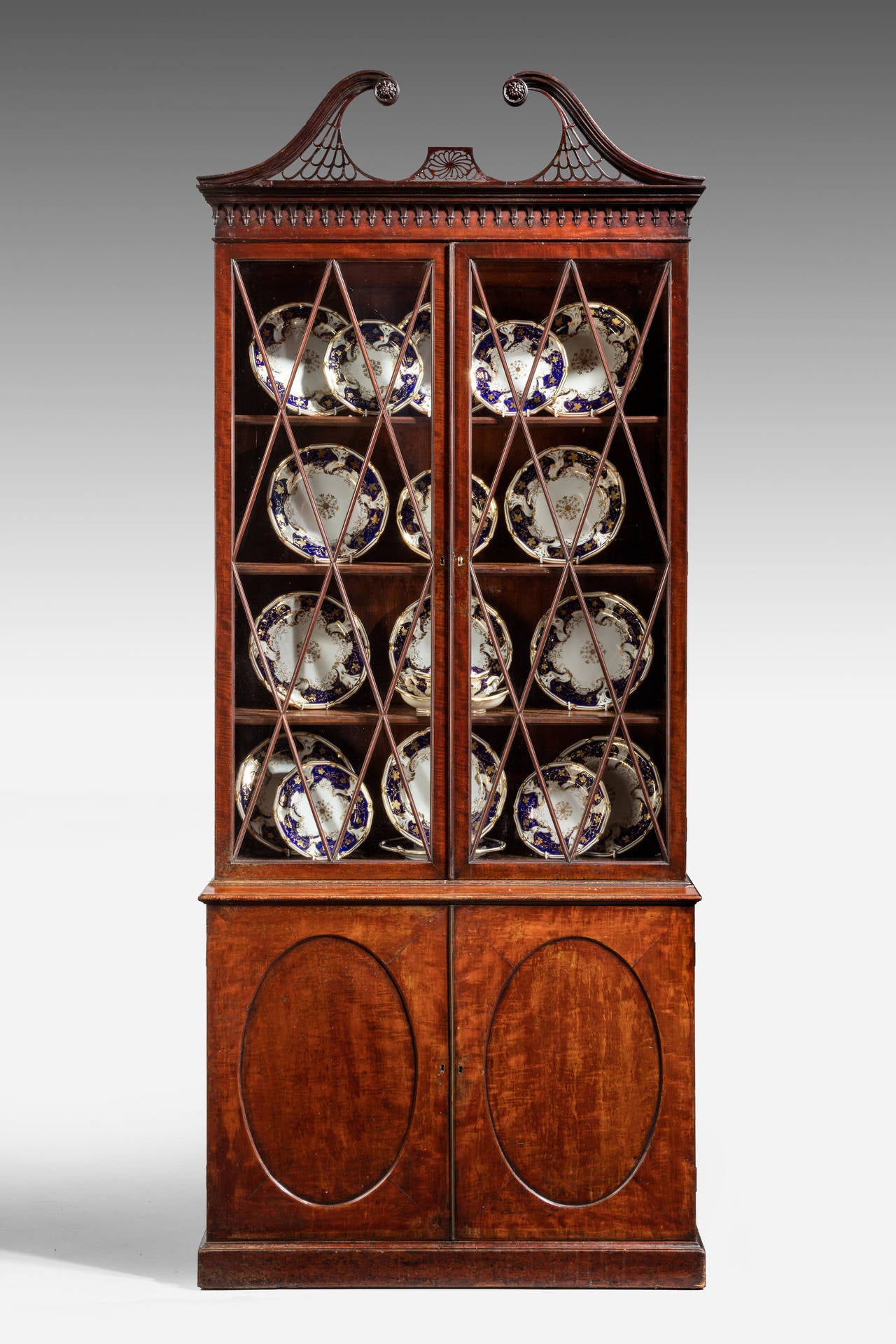 A very fine George III period mahogany bookcase. The drawers to the base with inset contrasting oval timbers. The top with diamond shaped glazing bars. Under a beautifully carved swan neck pierced pediment. Overall of exceptionally good quality.

