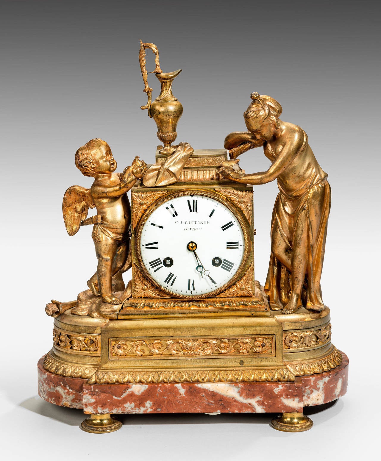 A good Louis XVI period gilt bronze mantel clock retailed in London by C J Whittaker, signed on the dial. Two figures supporting the central mechanism, with a dark gold and white moulted and marble base.