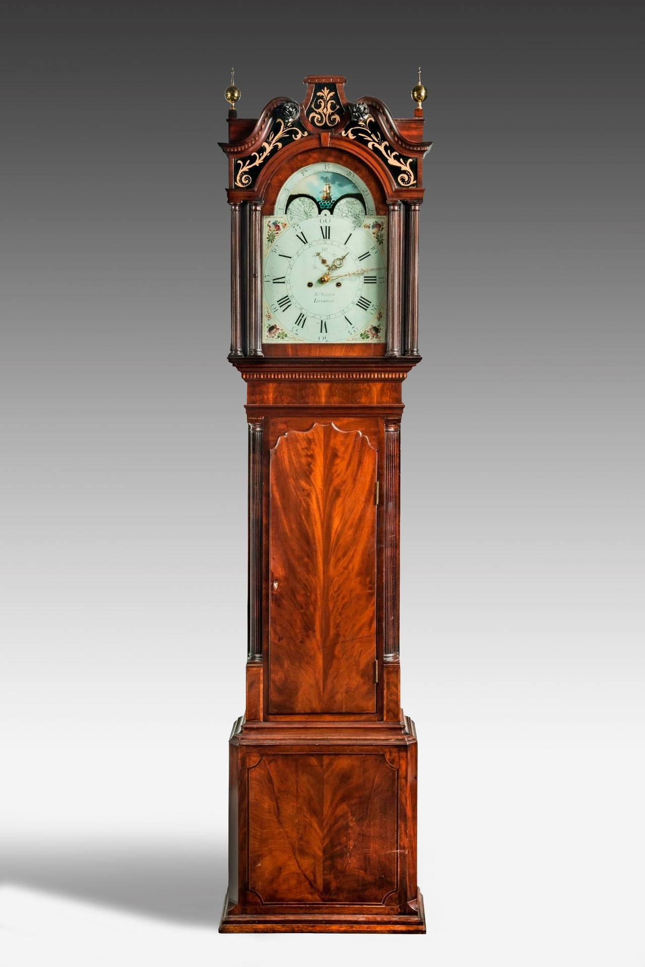 18th century longcase clock by James Cawfon of Liverpool with eight day movement. The swan neck pediment with boxwood dental moulding within with églomisé panels above the two brass finials. The painted dial with phases of the moon depicting a