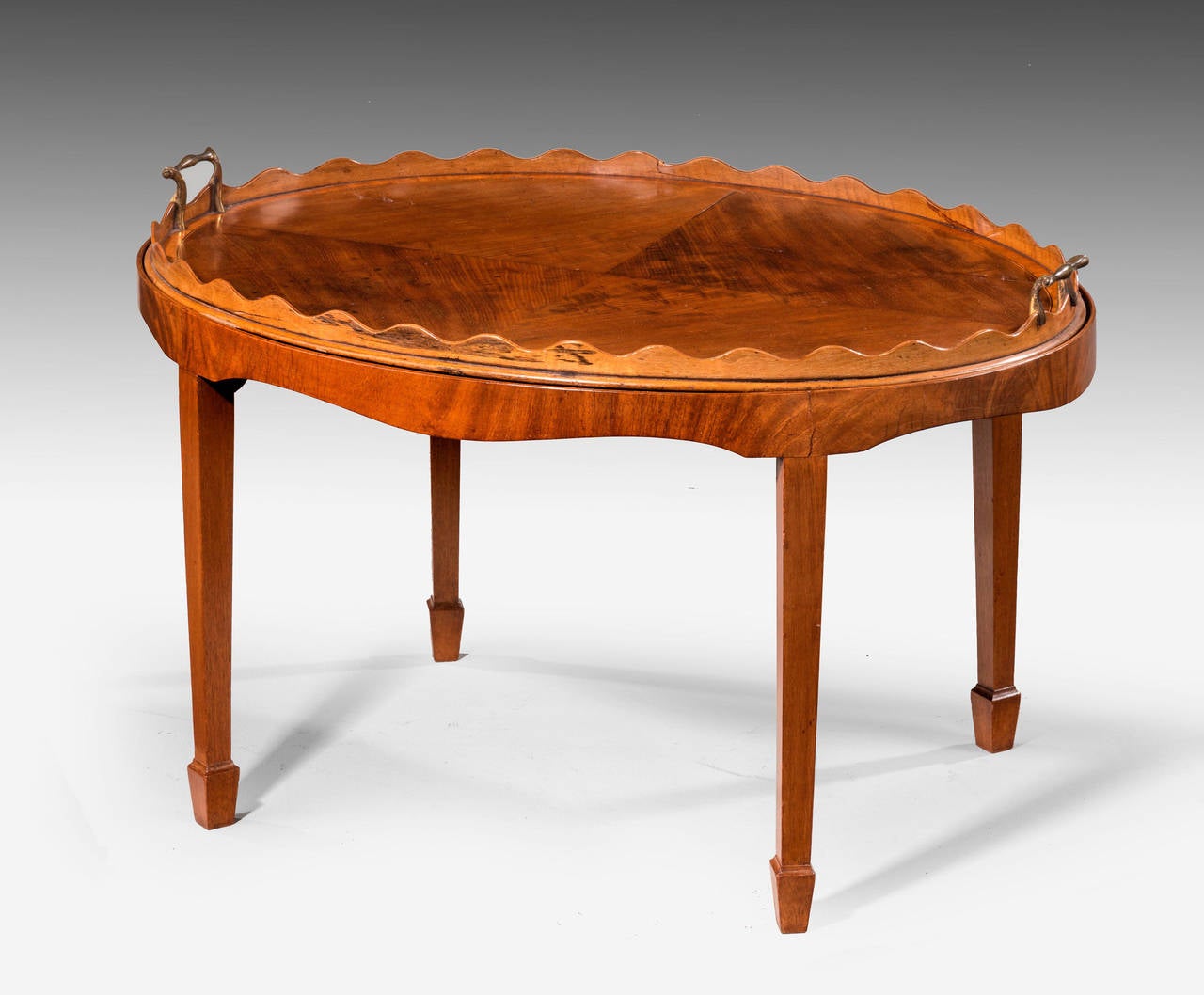 A very attractive George III style oval mahogany tray table. The tray lifting away with a quartered and a wavy top border and crossbanded in satinwood. On square tapering supports with block feet.