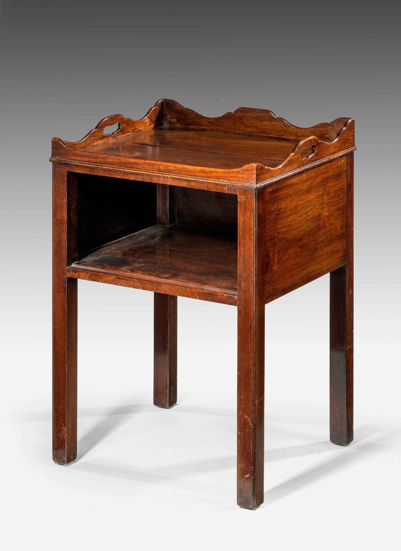 A George III mahogany nightstand. The top in two sections with beautifully figured timber under a wavy top border, with carrying handles.