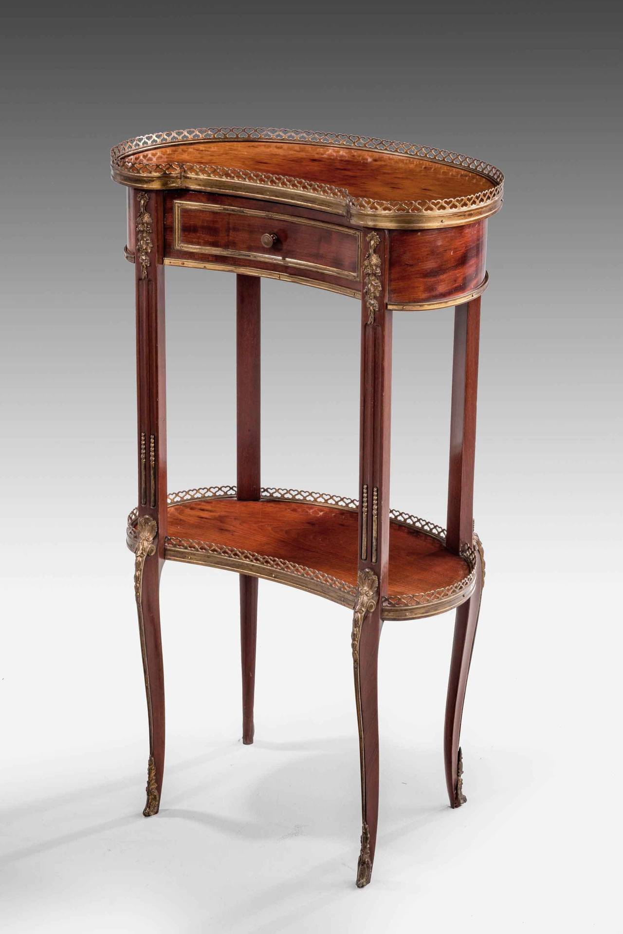 An exceptionally pretty 19th century plum pudding mahogany occasional table. The kidney shape with the top section incorporating a draw, under a pierced brass border. Well-cast and chiseled mounts to the supports and retaining the original