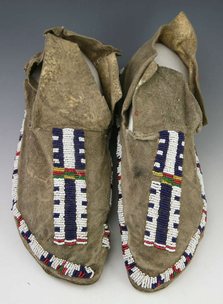 Hand tanned deer skin moccasins with minor bead loss, sinew sewn. Moccasins are supple to the touch and show signs of ethnographic wear (normal use).