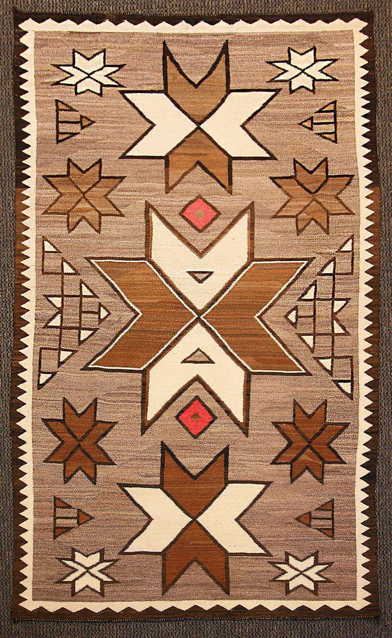 Large natural hand spun wool Navajo rug. There is a sleeve sewn onto one side of the textile so that it may be hung on a wall, could also be used as a floor rug.